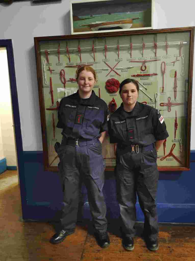 Photo of two Cadets in front of some knot examples